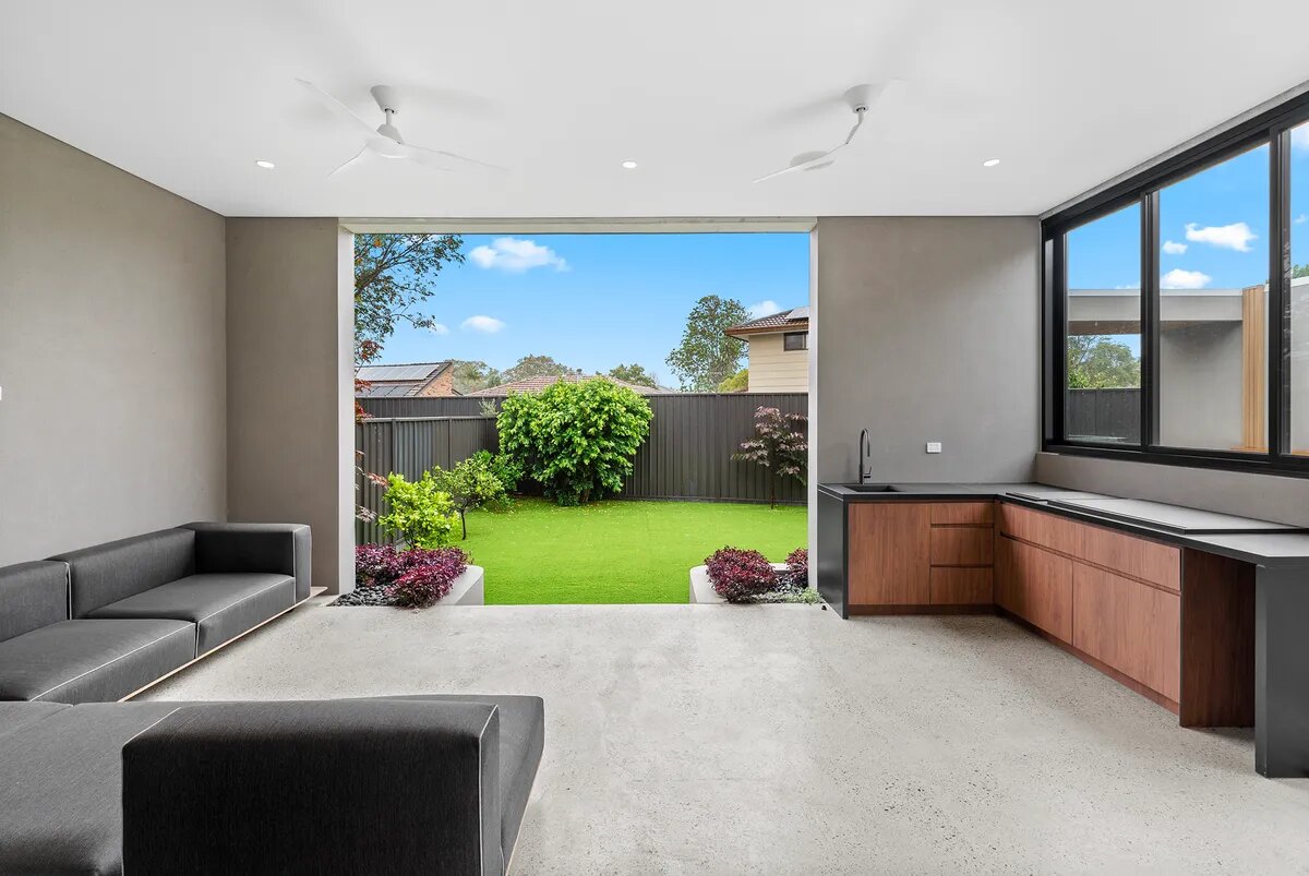 Covered outdoor entertaining area opening onto a landscaped lawn