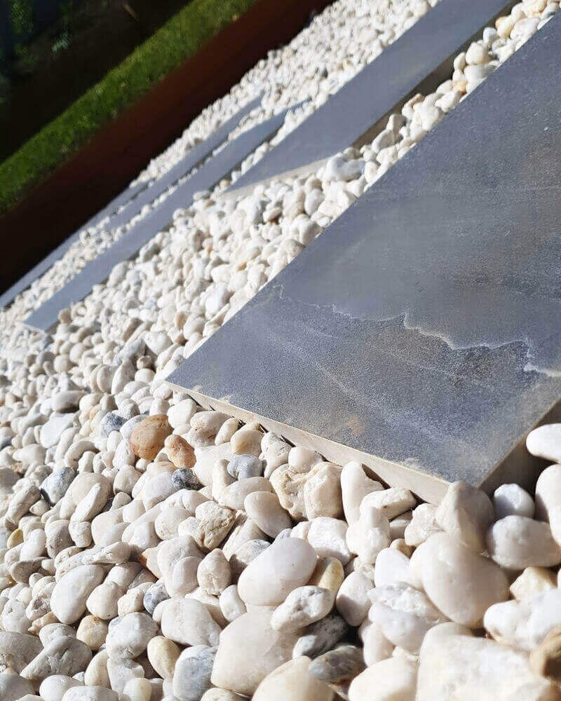 Stone pavers set within white river pebbles